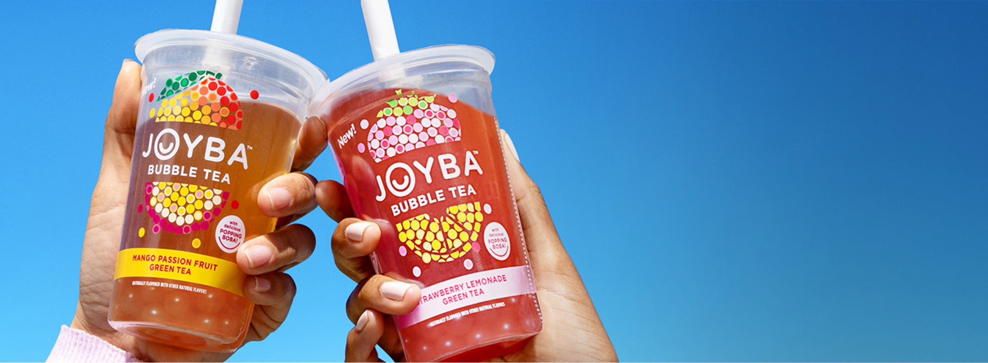 hands holding cups of Joyba tea